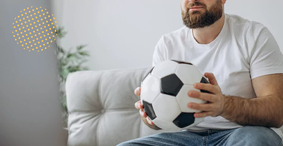 imagem de um homem sentado segurando uma bola de futebol