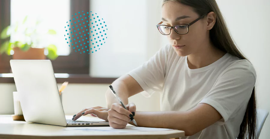 imagem de uma mulher sentada escrevendo e mexendo em um notebook ao mesmo tempo