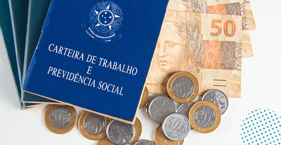 imagem de uma carteira de trabalho ao lado de moedas e notas de cinquenta reais