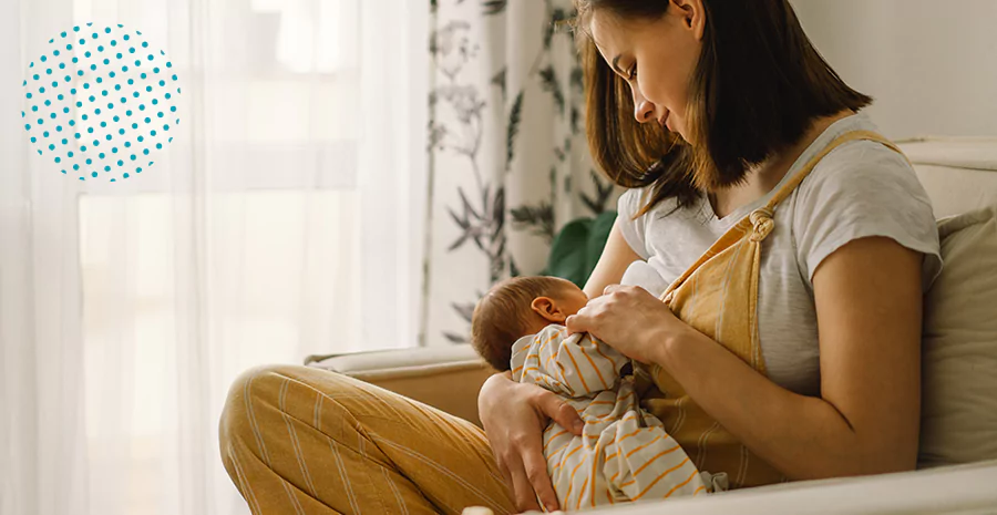 imagem de uma mulher sentada amamentando seu bebê de licença-maternidade