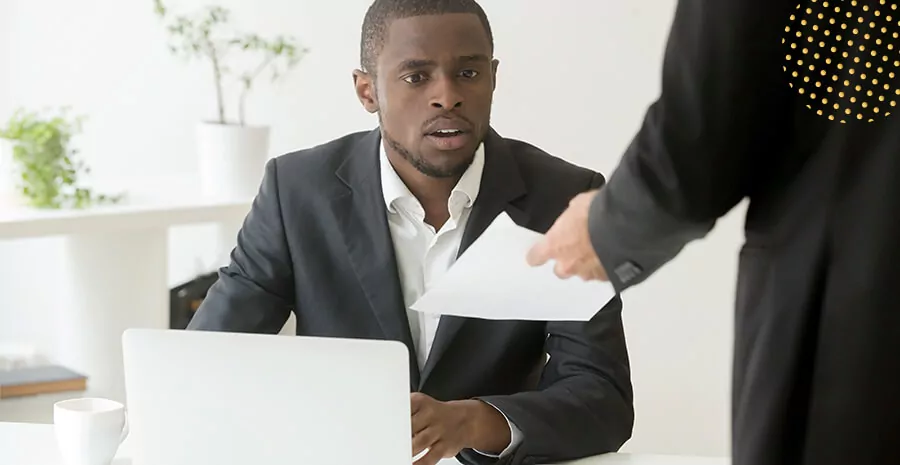 imagem de uma pessoa entregando um papel para um homem com expressão de espantado no local de trabalho