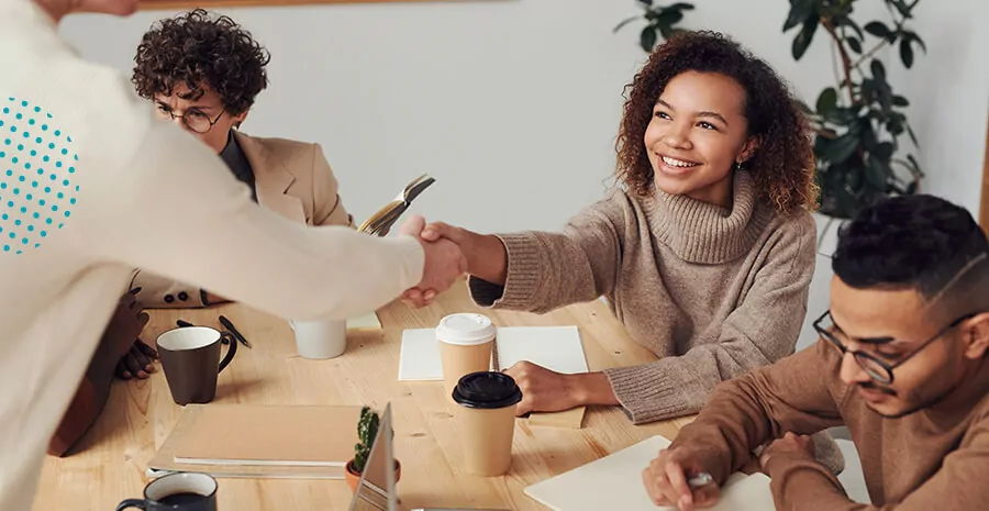 pessoas sentadas e conversando ao redor de uma mesa e uma passando papel para outra