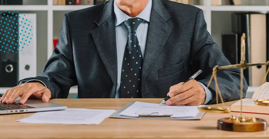 imagem de um homem de terno e gravata sentado escrevendo em um papel sob uma mesa