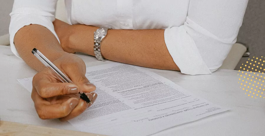 uma pessoa escrevendo com caneta em um documento impresso
