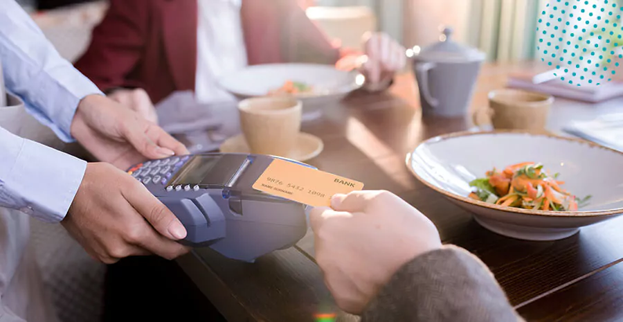 imagem de uma pessoa realizando um pagamento com cartão em um restaurante
