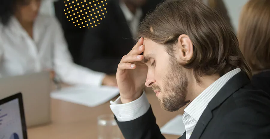 imagem de um homem sentado de frente para o computador com a mão na cabeça 