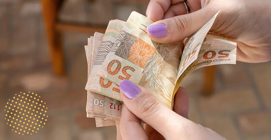 imagem de uma pessoa segurando várias cédulas de dinheiro a nota de cinquenta reais