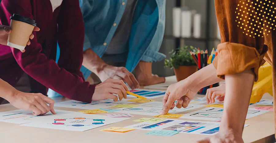 imagem de um grupo em uma reunião, em cima da mesa há post its