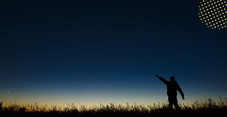 imagem de uma pessoa apontando para um céu estrelado 