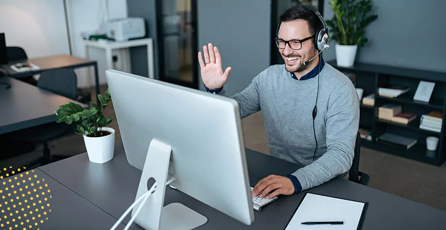 imagem de um homem sorrindo e acenando para a tela do computador