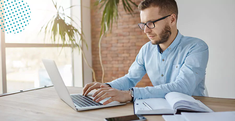 imagem de um homem de camisa azul digitando em um notebook 