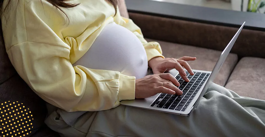 imagem de uma mulher grávida digitando em um notebook