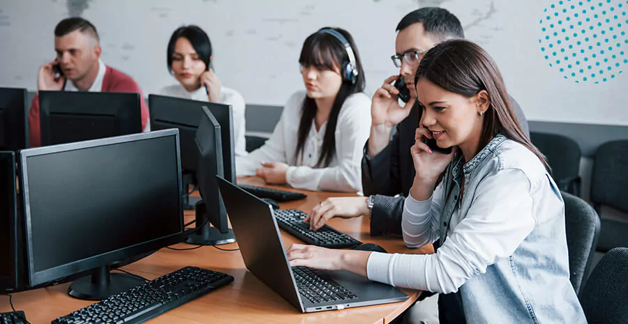 imagem de um grupo de cinco pessoas trabalhando na frente de computadores e falando ao telefone