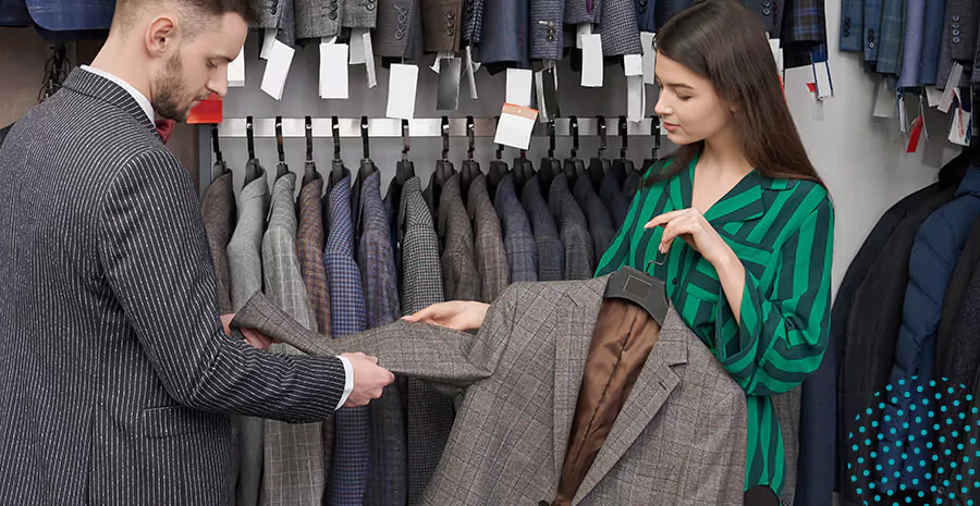 imagem de uma mulher vendendo um terno para um homem em uma loja