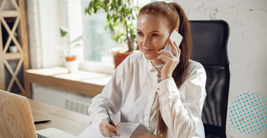 imagem de uma mulher falando ao telefone e anotando no papel