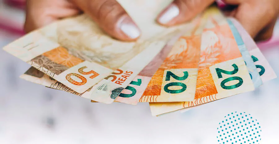 imagem de uma pessoa segurando notas de dinheiro de vinte e cinquenta reais