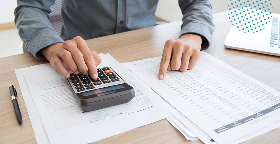 imagem de um homem usando a calculadora e comparando com dados em uma folha ao lado