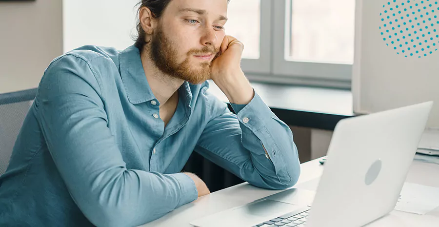 imagem de um homem entediado sentado na frente de um computador