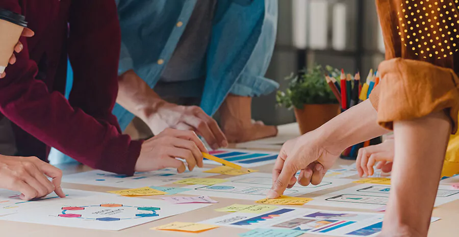 imagem de uma mesa cheia de papéis coloridos com pessoas apontando para eles