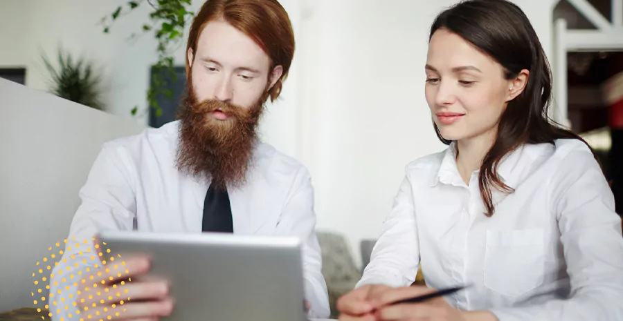 imagem de um homem e uma mulher sentados lado a lado olhando para um tablet