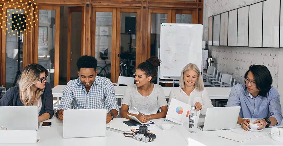 imagem de um grupo de pessoas sentado lado a lado em uma mesa mexendo em computadores