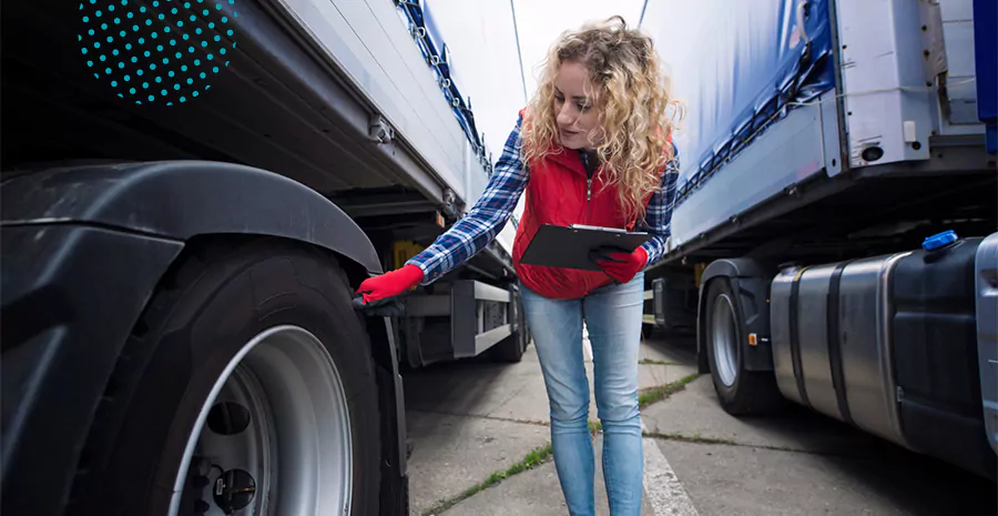 imagem de uma mulher checando o pneu de um caminhão