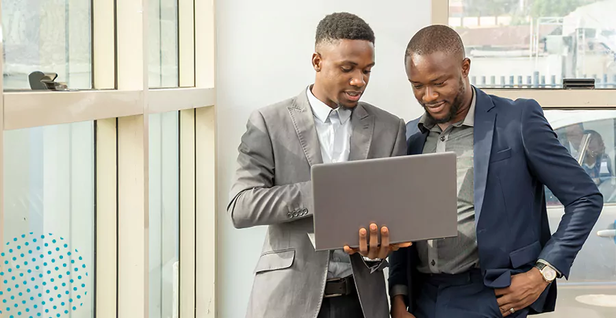 imagem de dois homens em pé segurando e olhando para um computador