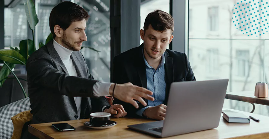 imagem de dois homens sentados em uma mesa olhando para um computador