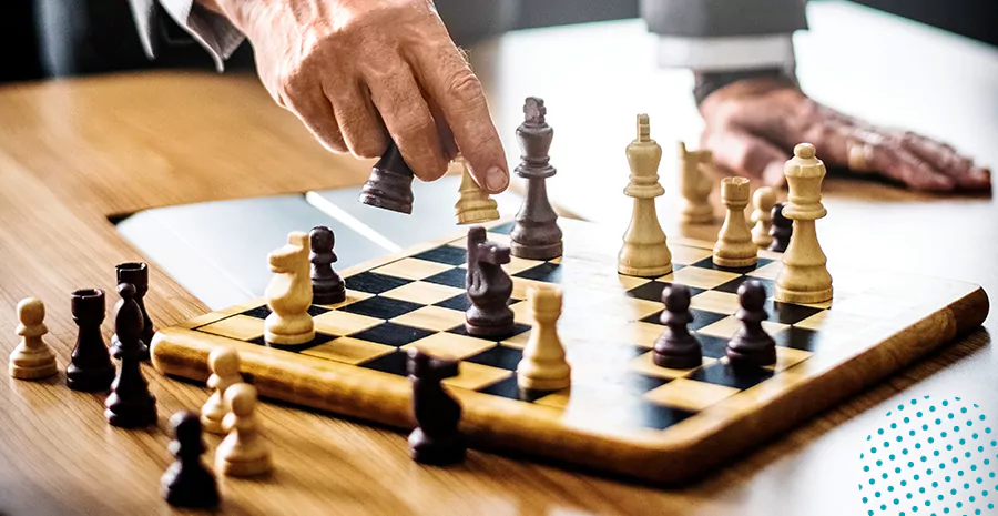 imagem de um homem segurando uma peça de xadrez na frente de um tabuleiro