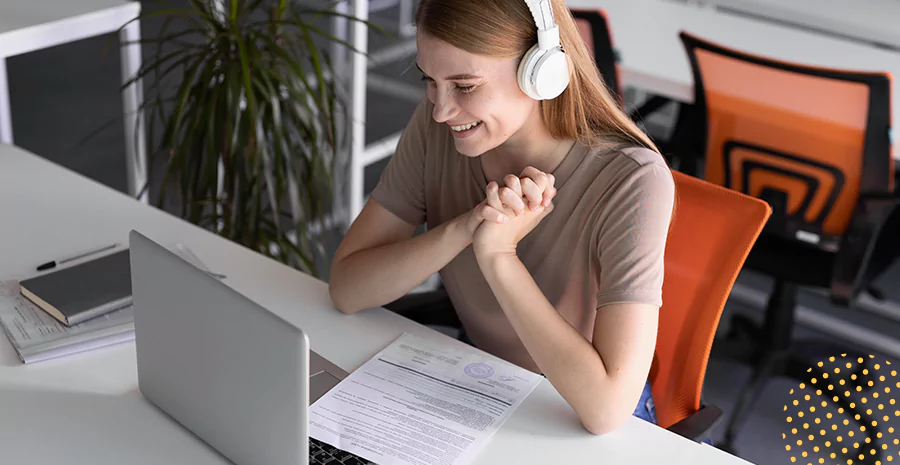 imagem de uma mulher sorrindo sentada na frente de um computador e usando fones de ouvido