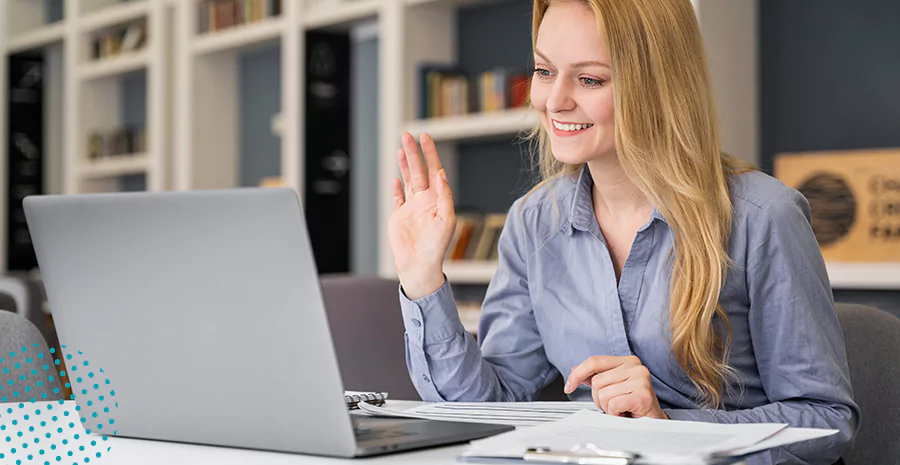 imagem de uma mulher sentada na frente de um computador erguendo a mão