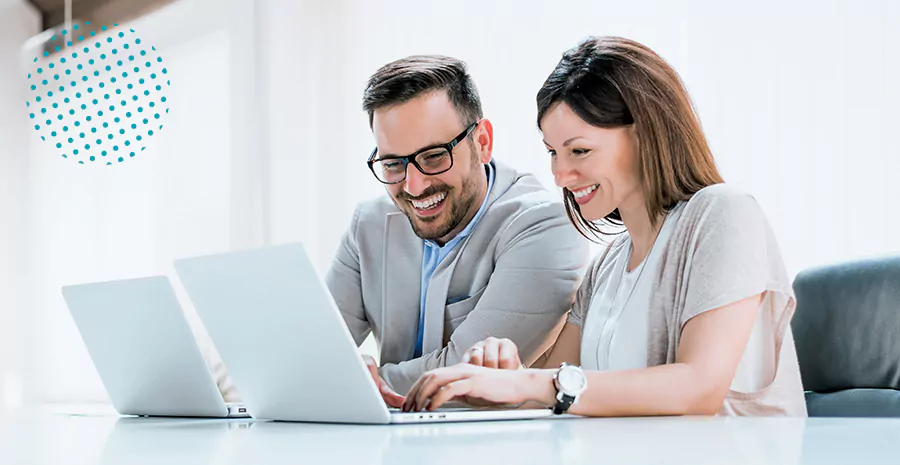 imagem de um homem e uma mulher sentados na frente de um computado sorrindo