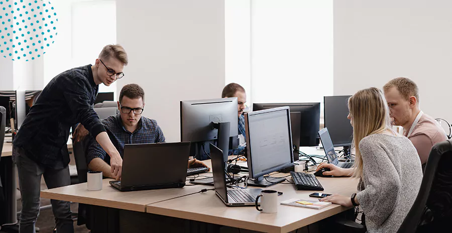 imagem de uma mesa de escritório com pessoas sentadas na frente de computadores