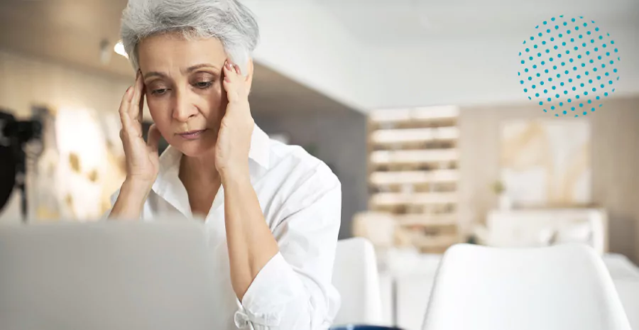 imagem de uma mulher preocupada sentada na frente de um computador com as mãos no rosto