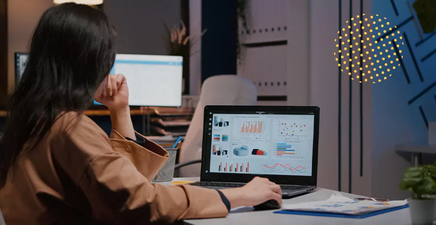 imagem de uma mulher sentada na frente de um computador olhando para gráficos