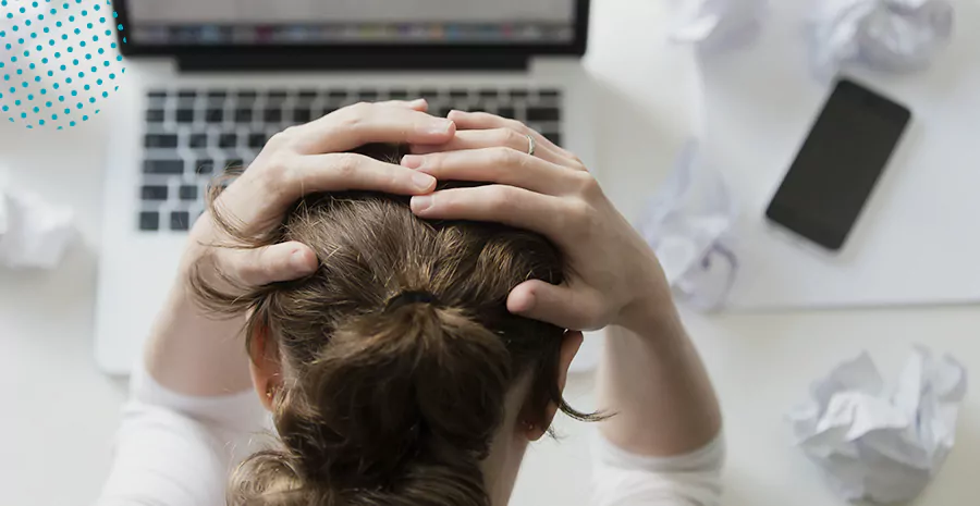 imagem de uma mulher sentada na frente de um computador colocando as mãos na cabeça