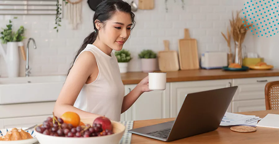 imagem de uma mulher segurando uma xícara e olhando para um computador