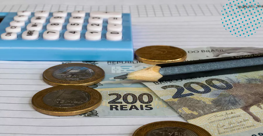 imagem de uma calculadora, um lápis, notas de duzentos reais e moedas