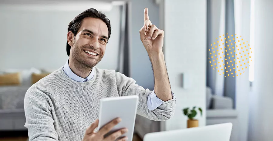 imagem de um homem sorrindo segurando um tablet e levantando a mão