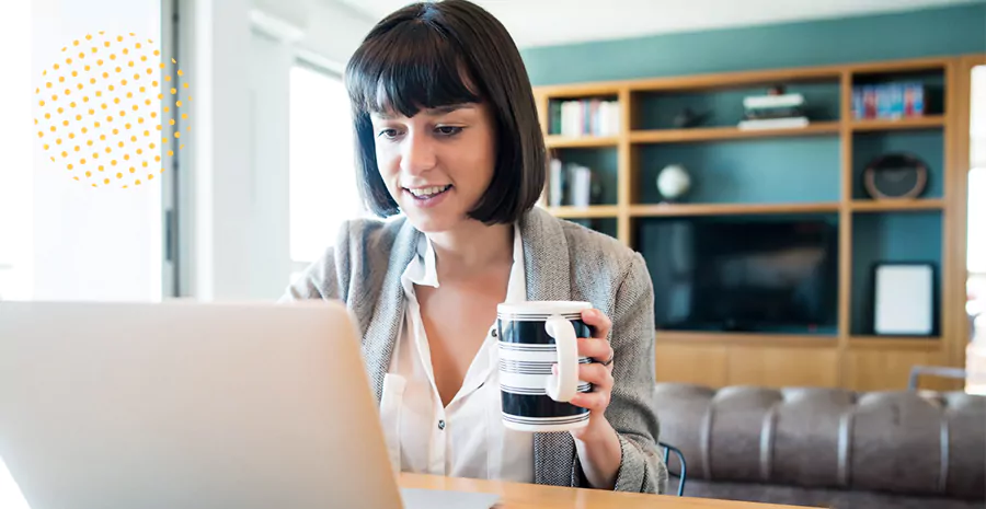 imagem de uma mulher sentada na frente de um computador e segurando uma xícara