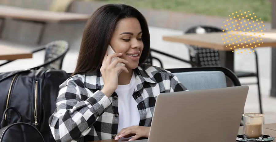 imagem de uma mulher sentada na frente de um computador falando ao celular