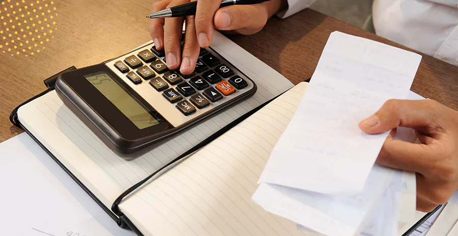 imagem de uma pessoa usando uma calculadora e segurando folhas de papel