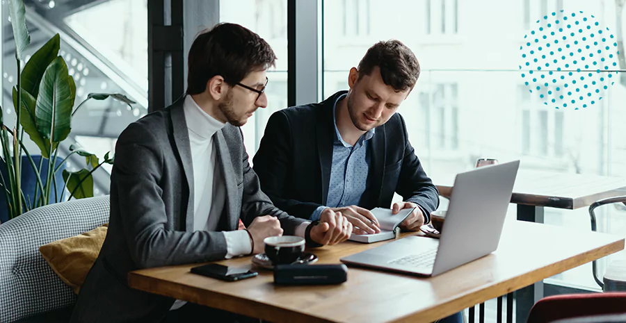 imagem de dois homens sentados na frente de um computador conversando