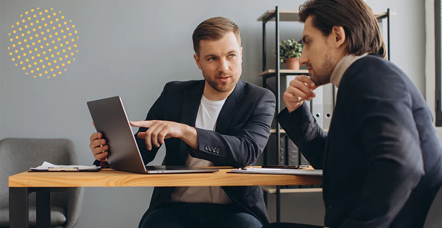 imagem de um homem sentado mostrando um tablet para outro homem sentado ao seu lado