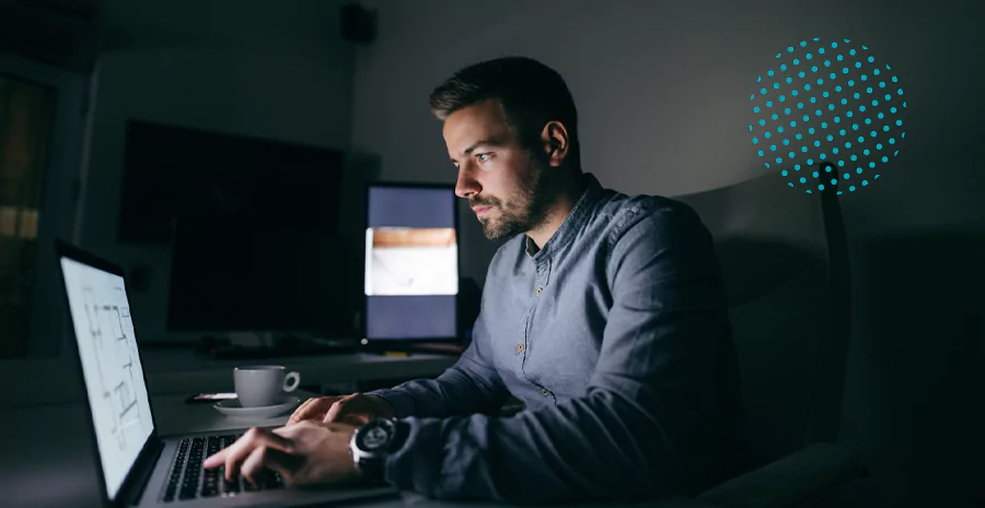 Homem em um quarto escuro mexendo em um notebook