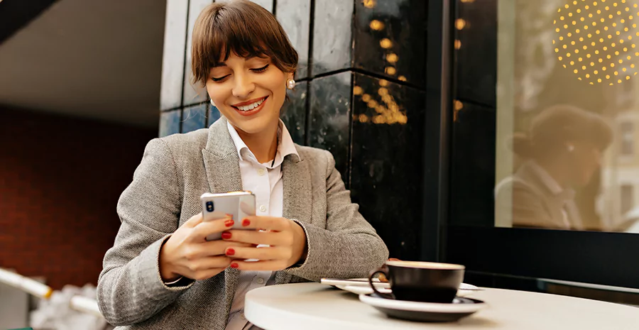 Uma mulher sorrindo observando o celular