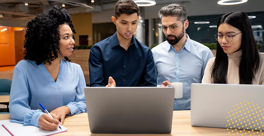 Grupo de colaboradores conversando em frente a um notebook