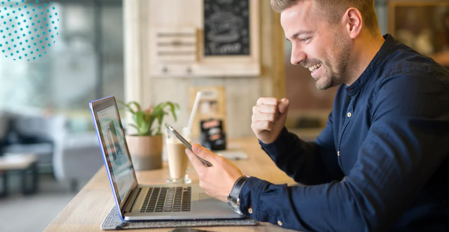 Um homem comemorando em frente a um notebook