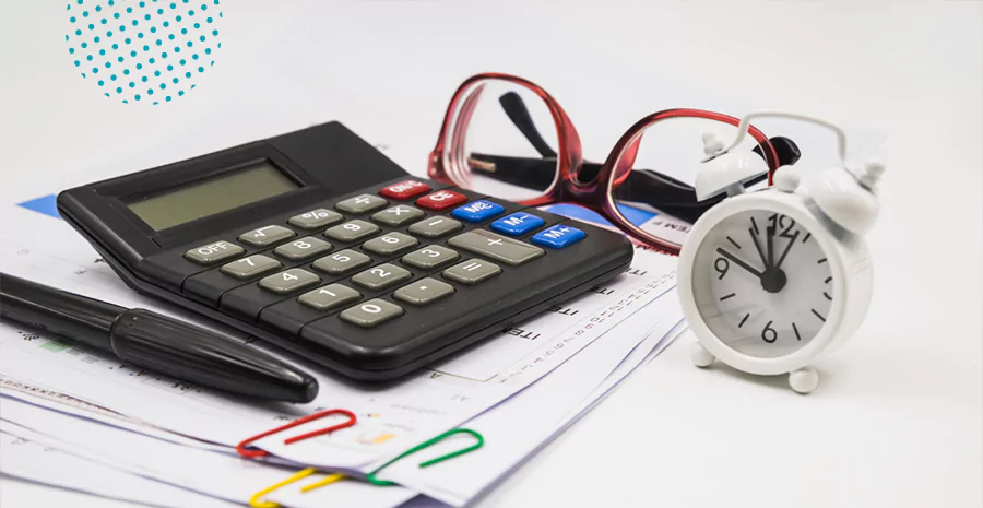 Calculadora, relógio e óculos em cima de papeis