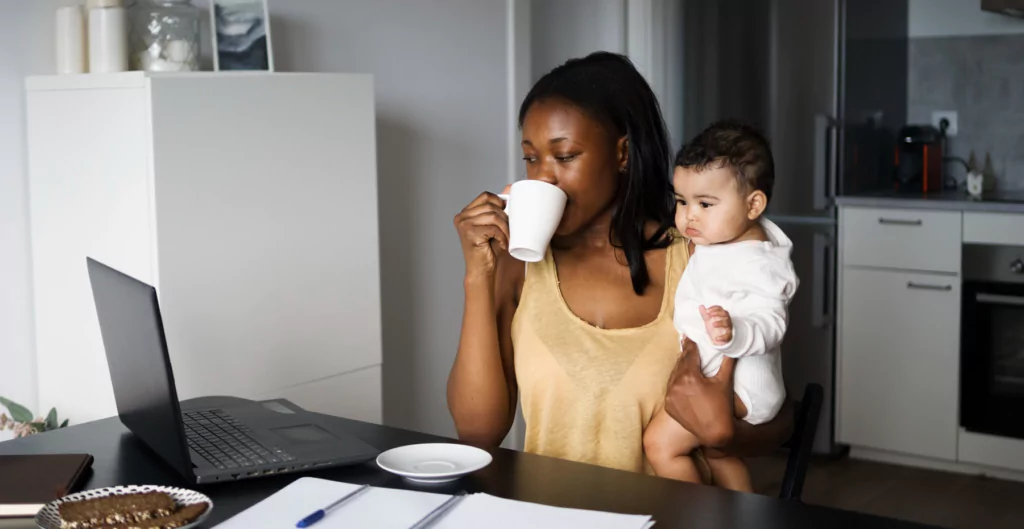 Mulher tomando café enquanto segura um bebe